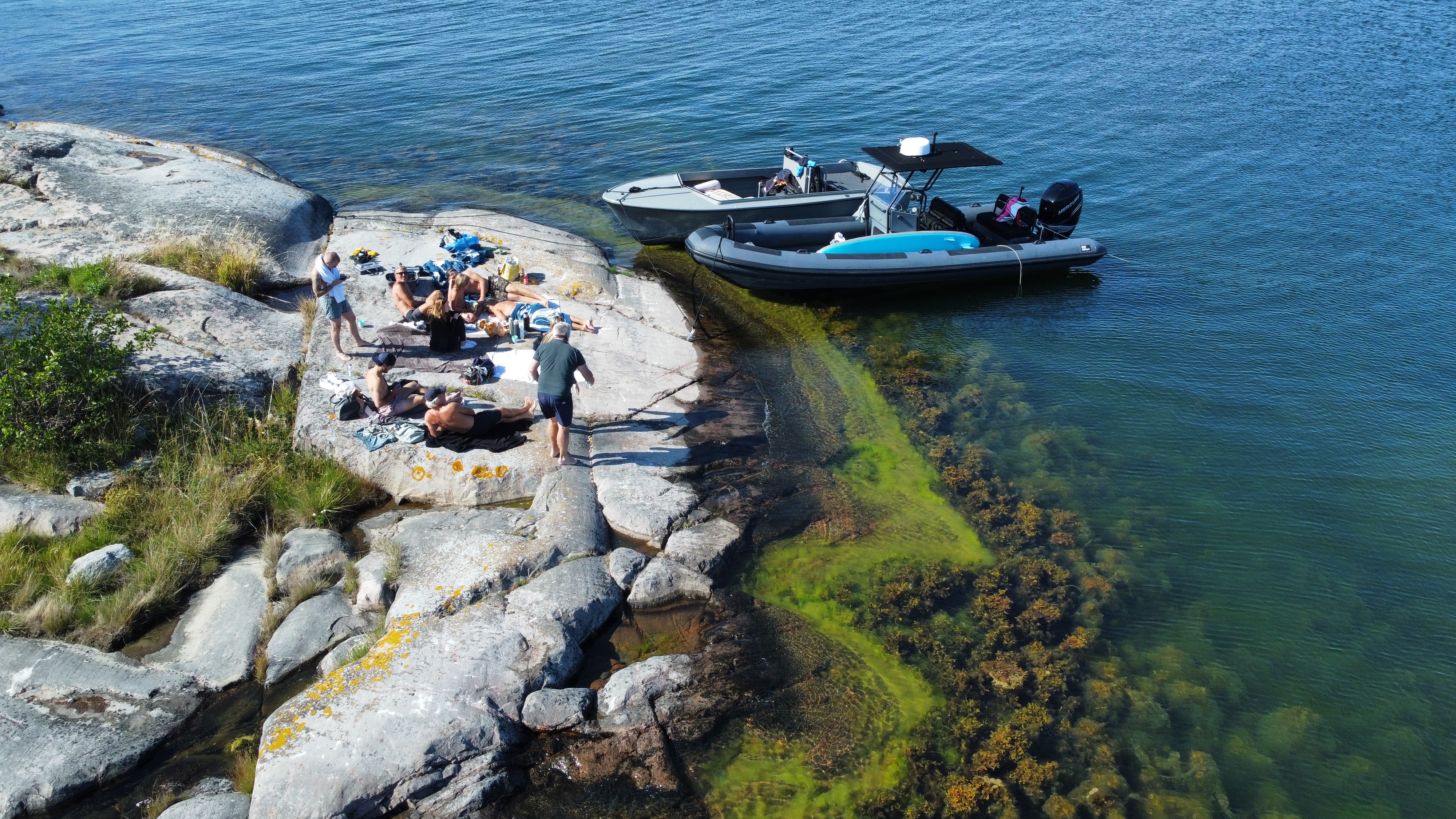 Friends on a rocky island next to two boats